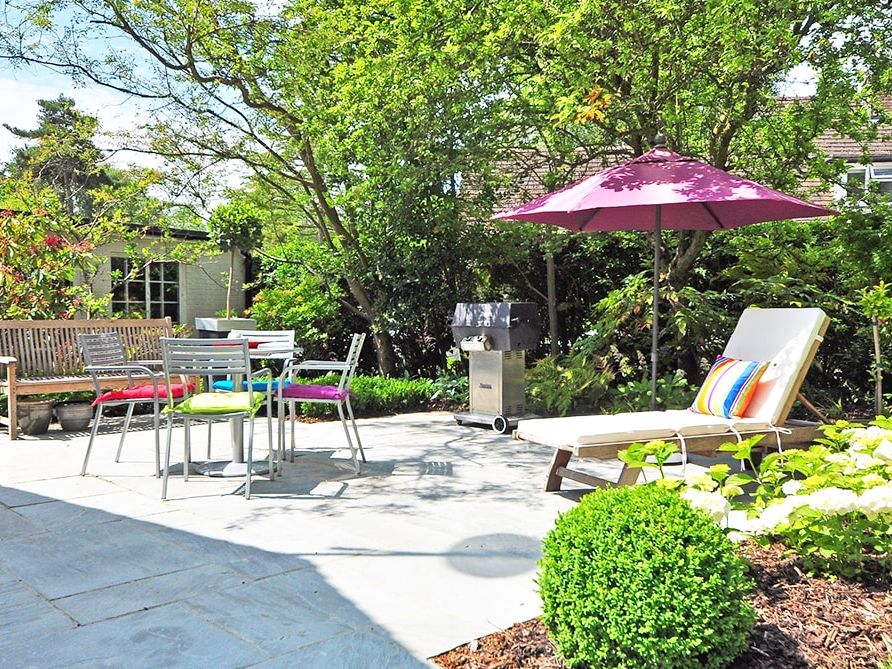 Gartenterrasse mit Pergola, Sonnenschirm und Bepflanzung